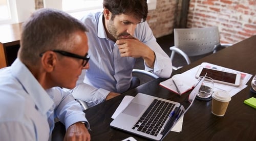 two guys looking at a laptop